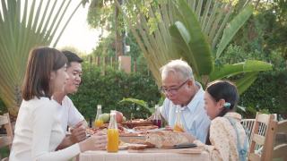 亚洲退休的爷爷和漂亮的孙女在家里的花园里享受着披萨。有家庭观念的退休老人快乐生活。视频素材模板下载