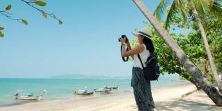 亚洲美女在周末度假的海边用相机拍照。快乐独自旅行的概念。4 k慢动作。