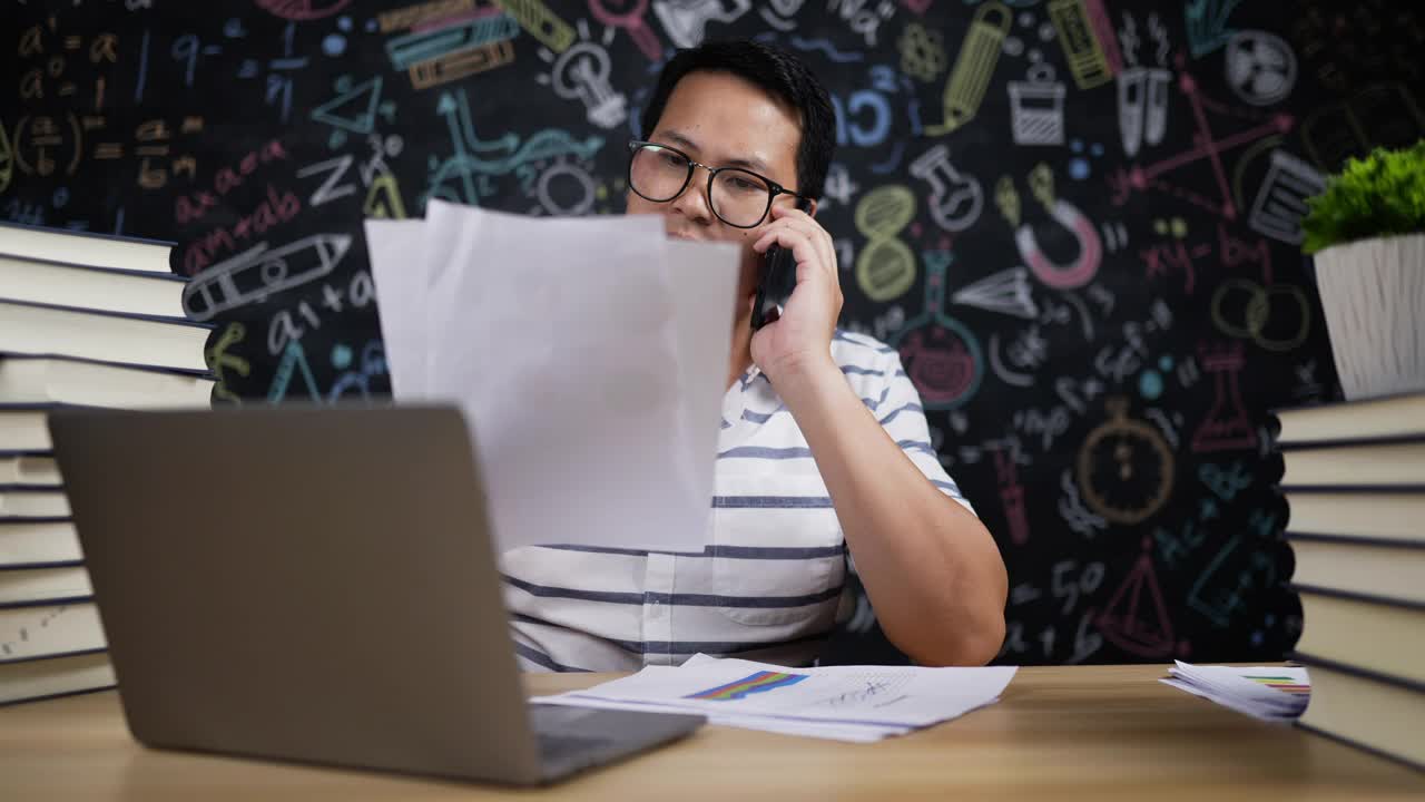 年轻的教师在检查报告时用智能手机聊天