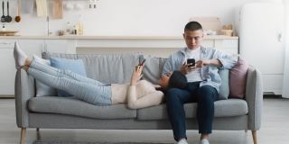 亚洲夫妇用智能手机在家沙发上放松