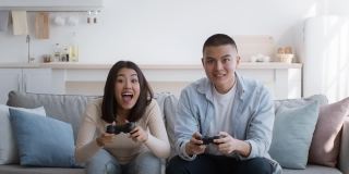 快乐的中国夫妇玩电子游戏在家里玩得开心