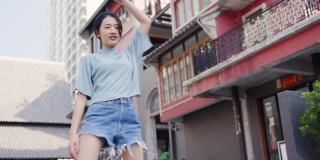 美丽的亚洲少女高兴地在城市跳舞。舞蹈锻炼使你有健康的身体。锻炼身体有益健康。周末活动快乐生活理念