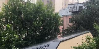 强烈的倾盆大雨。外面是绿树，城市的住宅楼