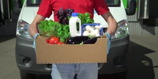 志愿者拿着盛有食物的盒子，社会救助。特写男子手拿捐赠蔬菜的盒子