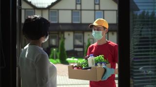 男人快递员送一盒食物给女人Spbd。志愿者捐赠新鲜蔬菜视频素材模板下载