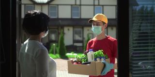 男人快递员送一盒食物给女人Spbd。志愿者捐赠新鲜蔬菜