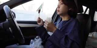 亚洲女司机在车上吃街头食物的假期早餐雾蒙蒙