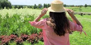 迷人的女孩在优雅的粉红色衣服愉快地站在田野的花在夏天。有自由的感觉。美丽,漂亮。大自然的力量，美丽