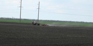 农用拖拉机在日落时在田里耕作。农业机械，农业自然季节性春工