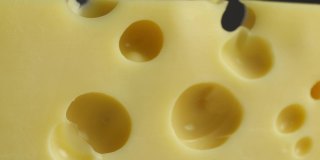 瑞士奶酪与孔靠近，奶酪旋转在慢动作背景视频