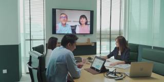 亚洲白领与公司员工进行视频会议会议讨论在会议室董事会与外国投资者进行视频会议。公司并购业务会议