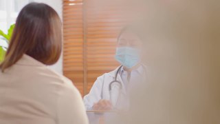 专业的亚洲女医生为患者提供健康咨询，为健康生活提供健康咨询，在医院穿着白大褂带着听诊器与患者交谈，医生和患者的概念视频素材模板下载