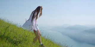 女孩走在草地上，看着加尔达湖美丽的全景