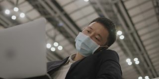 亚洲精力充沛的商人，戴着防护面罩，在等待飞机到达时接听在线工作电话-库存视频