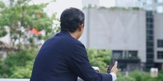 一名亚洲男子在视频电话会议中看着智能手机