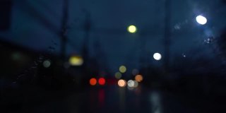 关闭了。下雨天在路上开车。从车流中聚集的模糊光线，雨水打在前镜上。视频缓慢的运动。