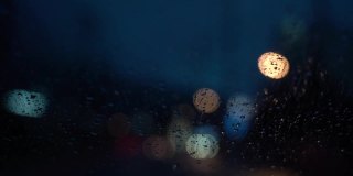 视频缓慢的运动。在雨夜开车。从车流中聚集的模糊光线，雨水打在前镜上。