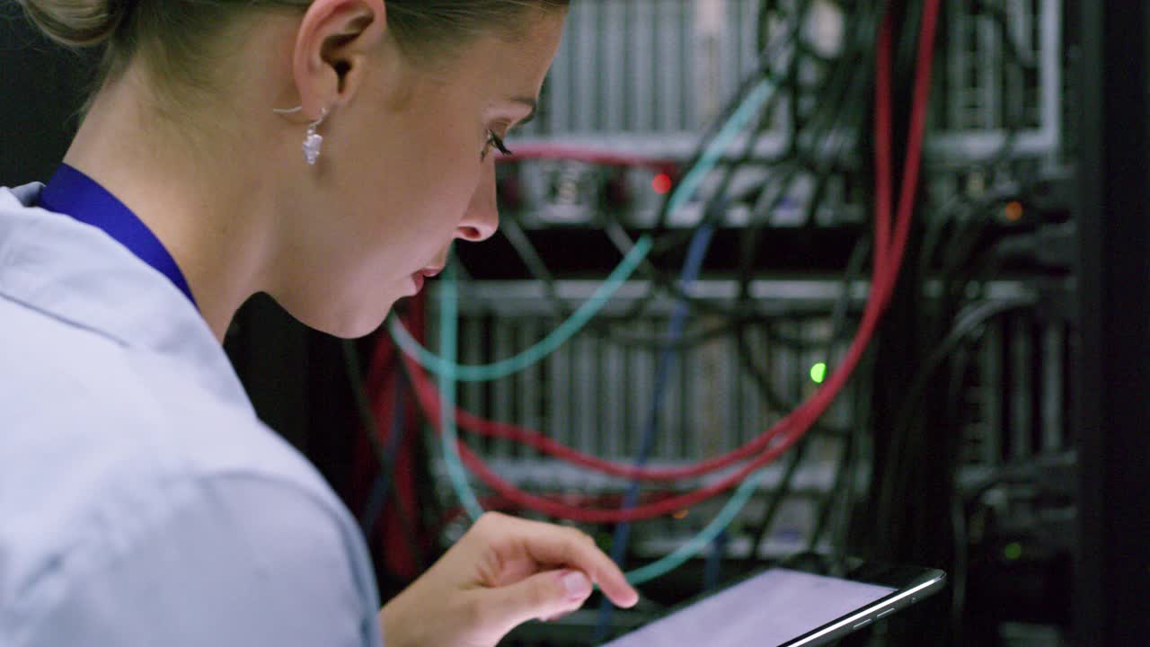 一名年轻女子在服务器室使用数字平板电脑的4k视频片段
