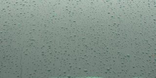 雨滴滴在车窗上。表面液体的积聚。