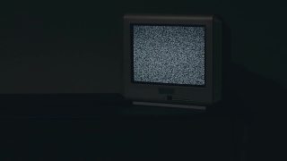 破旧的电视机-在黑暗的房间里，黑色的桌子上放着旧的银色电视机视频素材模板下载