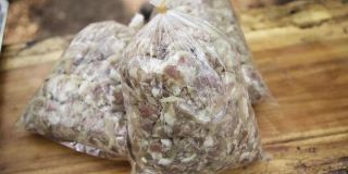 塑料袋里的酸猪肉在砧板上特写，塑料袋里的腌猪肉