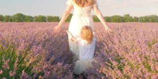 日落时分，母女俩走过一片薰衣草田。热爱自然，香薰，香薰油。自由，幸福，微笑，家人在一起。美丽的花朵。户外生活方式