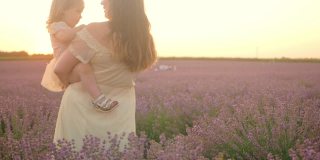 日落时分，母女俩在薰衣草地里。家庭和睦，阳光，香薰，石油生意。紫色的花。户外生活方式。美丽优雅。快乐,微笑,快乐