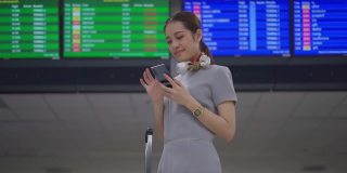 一名女乘客在机场候机楼办理登机手续前，用手机用数码登机牌检查她的航班