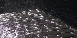 慢镜头特写:春天的雨水落入柏油路上的大水坑，淹没了街道。由于雨季的大雨，道路被淹。雨点落在被淹没的路上