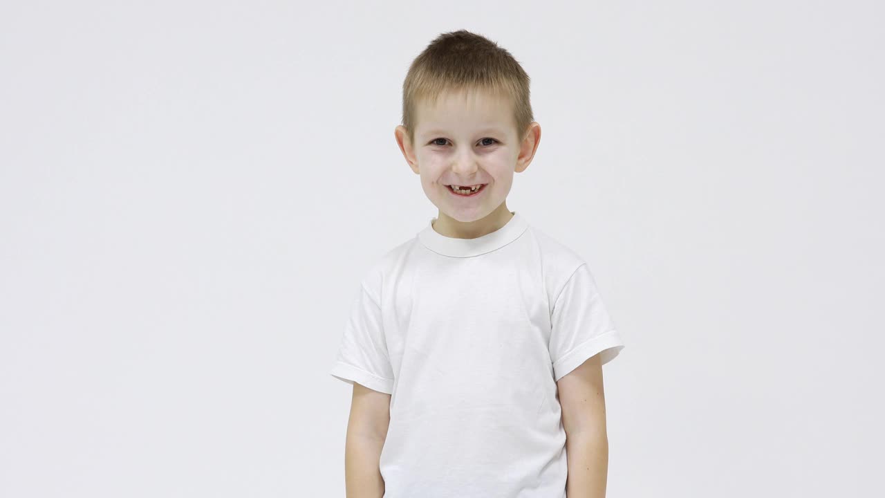 身穿白色t恤的快乐小男孩张开嘴，在白色背景上展示他的乳牙掉在哪里