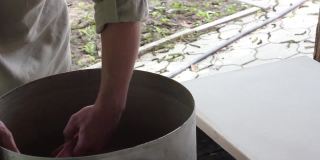 一个白人男性陶工准备液态黏土做造型，把它倒在木板上晾干