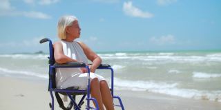 年长的亚洲妇女坐在轮椅上眺望大海