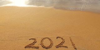 秋季的概念。海浪冲刷着2021年夏天沙滩上的文字