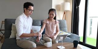 年轻的亚洲男医生在家中检查成年女性的血压