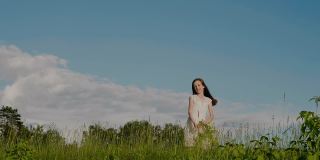 身穿白色连衣裙的快乐学龄少女抛出野花花环，在大自然的背景下跳跃