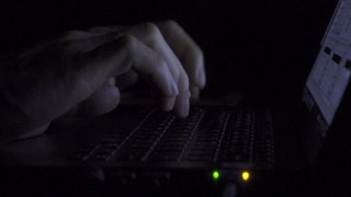 在光线较暗的情况下，利用屋内网线的光线敲打笔记本电脑的键盘视频素材模板下载