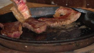 在铁锅里煎牛排。这家餐厅的专业厨师在家做饭。厨师把一块肉放在火上烤。煎烟。生肉蒸煮过程。视频素材模板下载