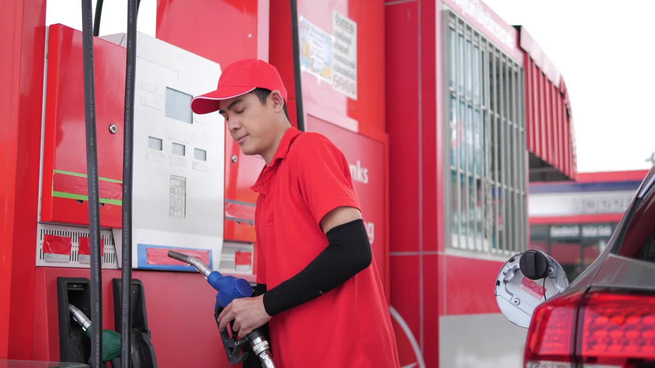 穿着工作服的亚洲工人在加油站给汽车加油