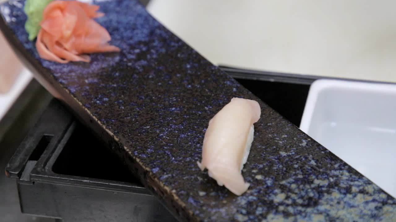 厨师的手在寿司盘上摆放鲈鱼手握寿司