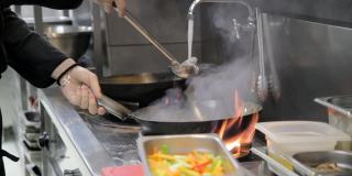 厨师用勺子将水倒在热油上，在煤气炉的火焰上