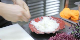 厨师的手把米饭捏成手握寿司的形状，再盖上海鲈鱼片