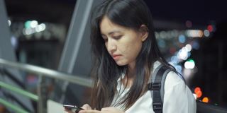 泰国一名年轻女子晚上站在走廊上使用智能手机。