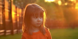 夏日公园里，小女孩微笑着抬头看日落。孩子们在户外的阳光下玩耍。