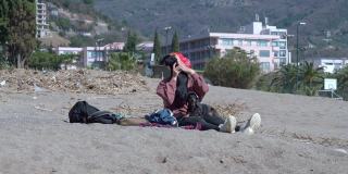 在阳光明媚的春天，带着太阳镜的女主人抱着小腊肠狗，在山上度假酒店附近的沙滩上消磨时光