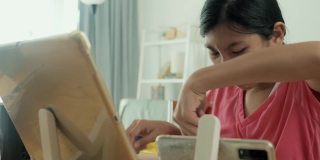 亚洲女孩在Covid-19期间在家学习在线课程，居家隔离生活理念。