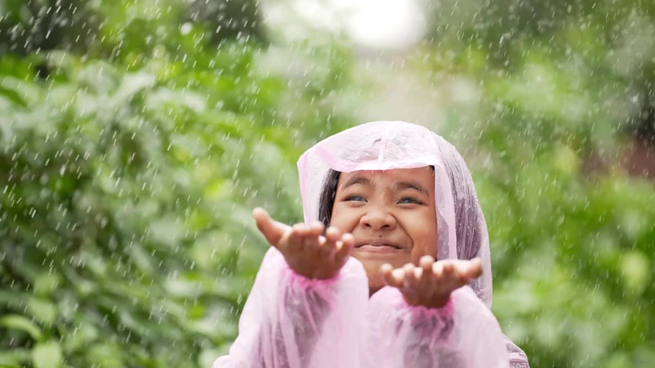 快乐的女孩穿上雨衣，伸出手