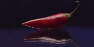 红辣椒放在玻璃表面，背景是燃烧的火焰。资料片。辣亚洲料理的概念。
