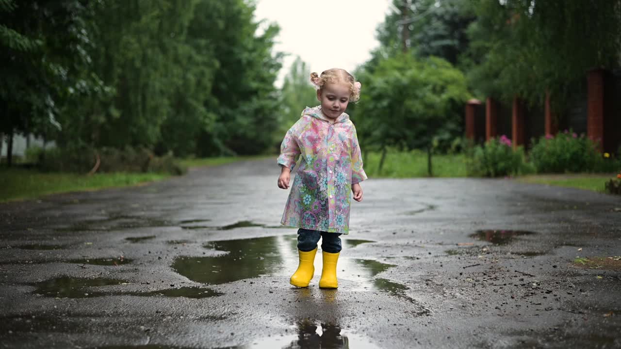 一个小卷发女孩在下雨天走在村庄的街道上