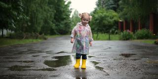 一个小卷发女孩在下雨天走在村庄的街道上