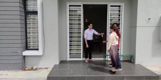 一对亚洲的中国夫妇从房地产经纪人那里拿到了新房钥匙，并参观了他们的新房